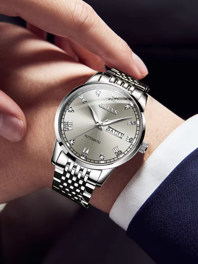 Silver wristwatch on a person's wrist with a dark background