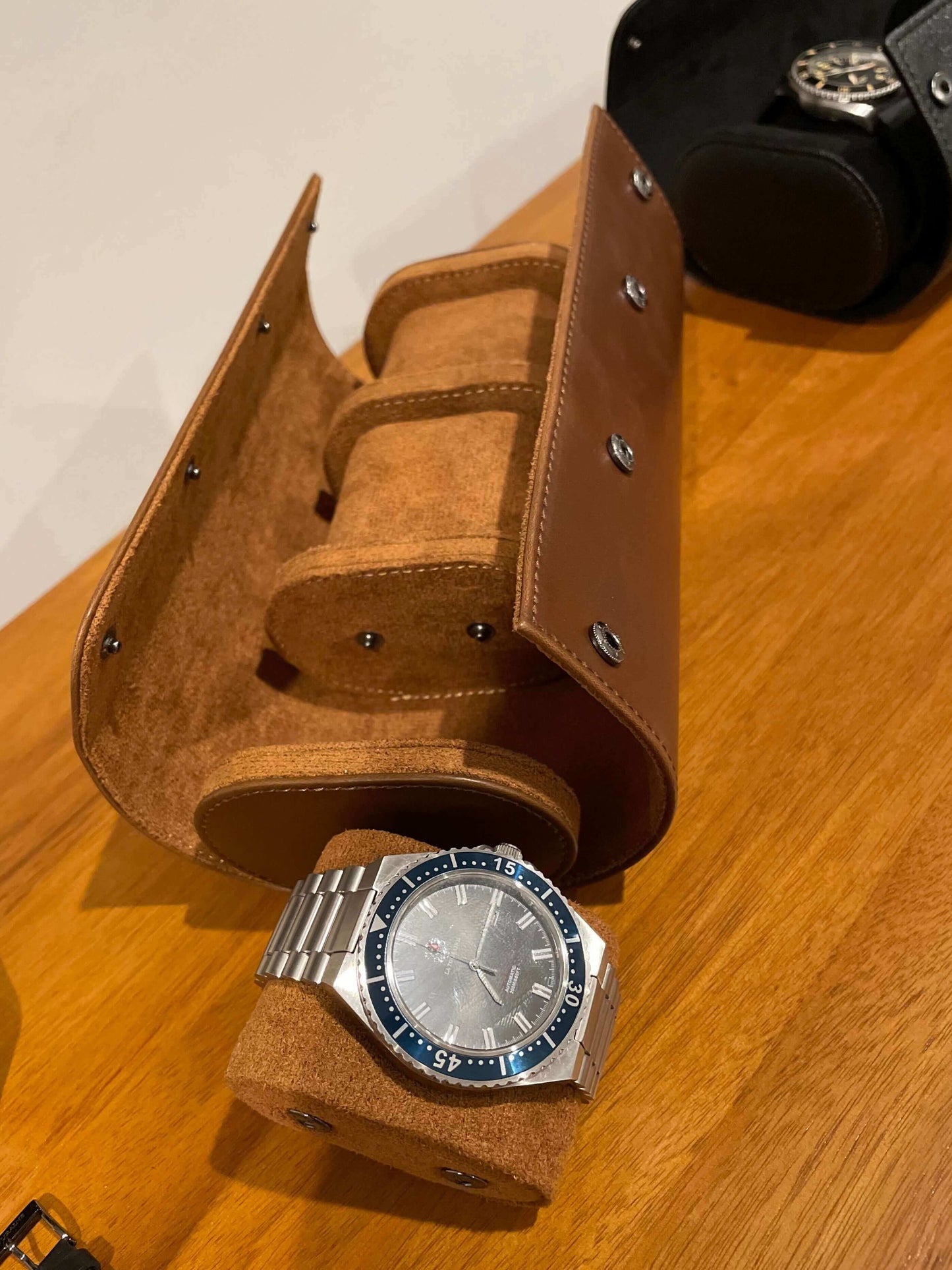 Watch with a brown leather case on a wooden surface