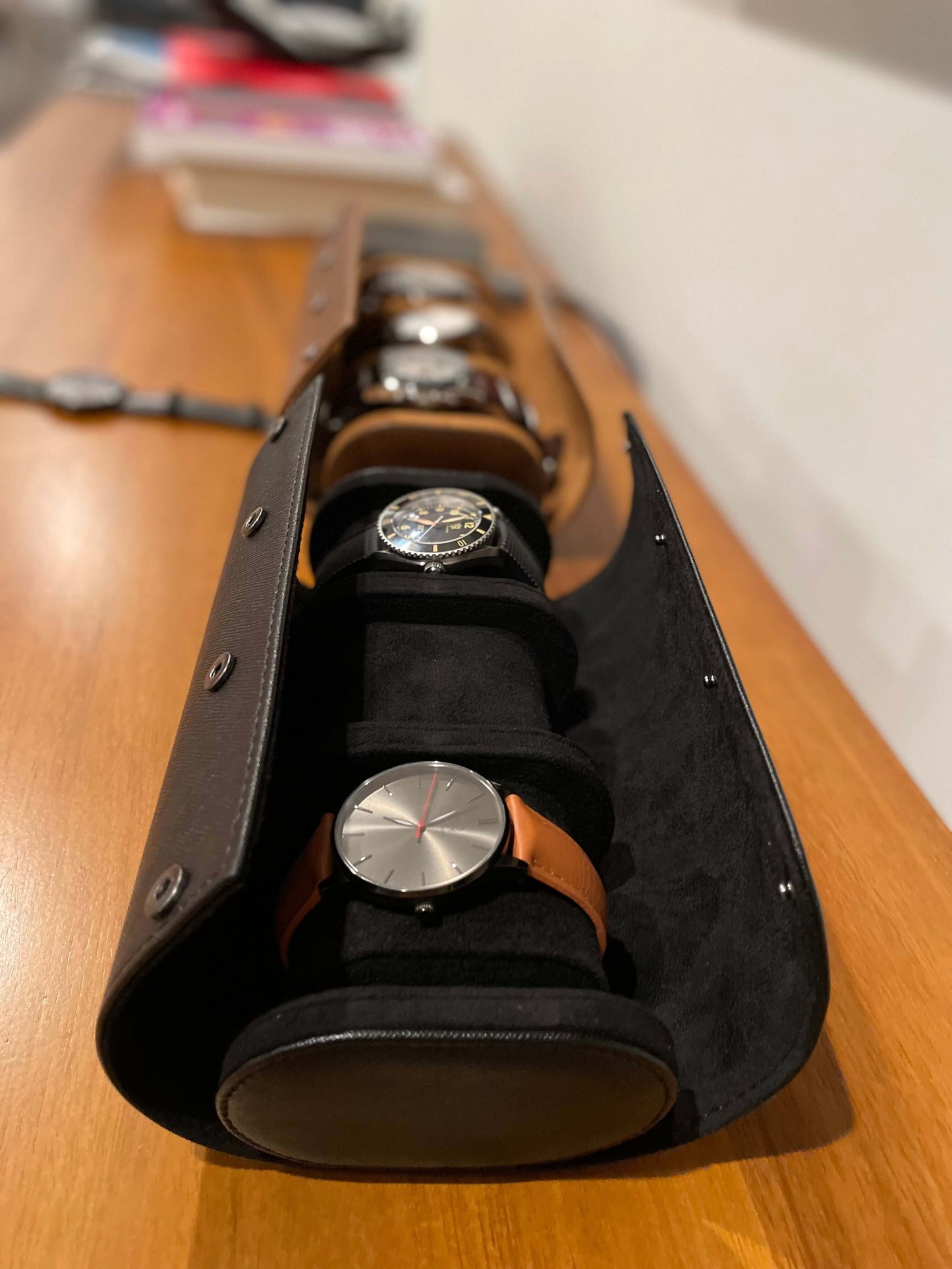 Black leather watch case with watches on a wooden surface